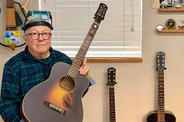 Guitar repairman Dan Erlewine holding an acoustic guitar