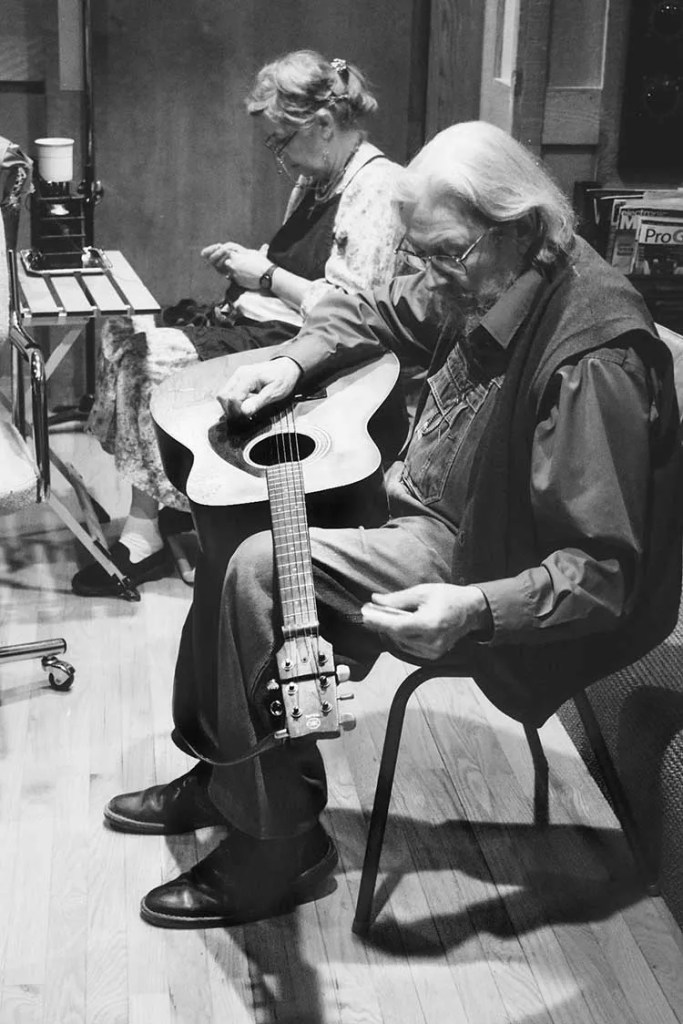 Norman Blake, seated, stringing his guitar. Photo by Christi Carroll