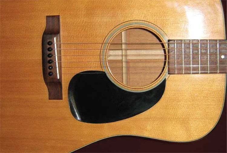 Vintage acoustic guitar with a shrinking pickguard.