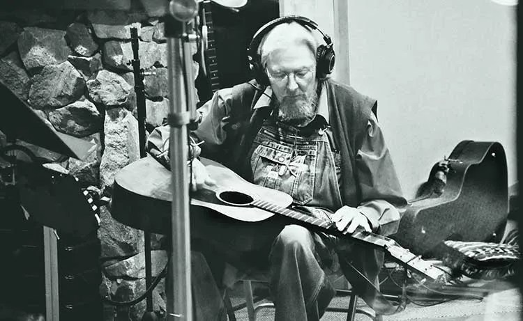 Norman Blake with headphones playing slide guitar. Photo by Christi Carroll