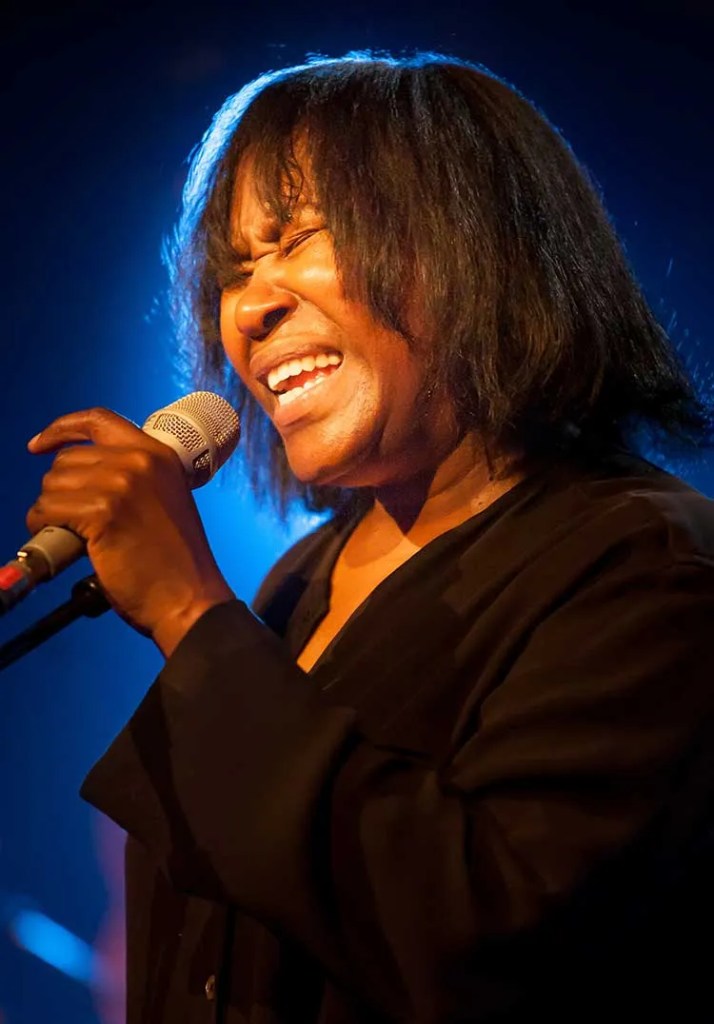 Joan Armatrading singing into a microphone