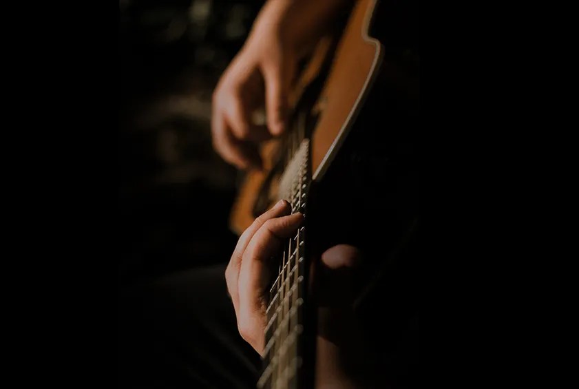 closeup of hands playing an acoustic guitar