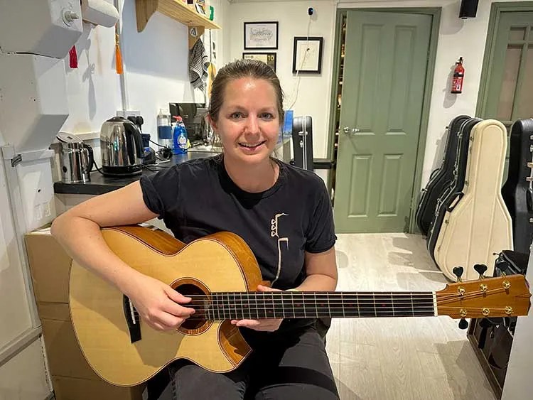 Rosie Heydenrych of Turnstone Guitars seated with one of her instruments