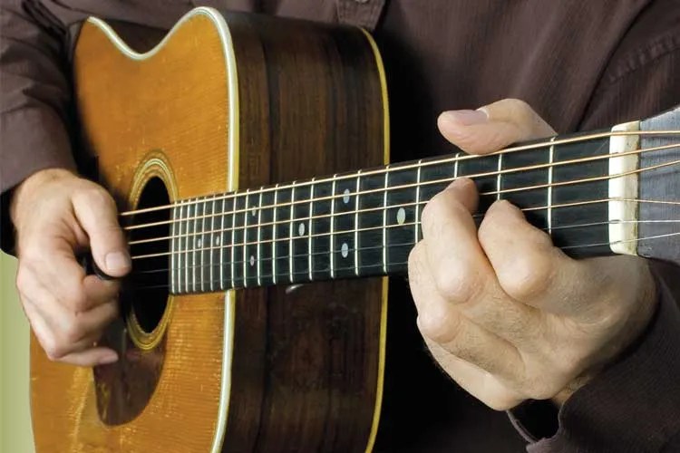 closeup of a musician playing and acoustic guitar