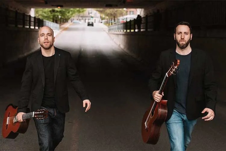 guitarists Adam Cicchillitti and Steve Cowan walking on a road