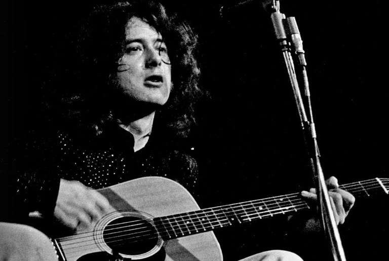 black and white photo of Jimmy Page seated playing his acoustic guitar