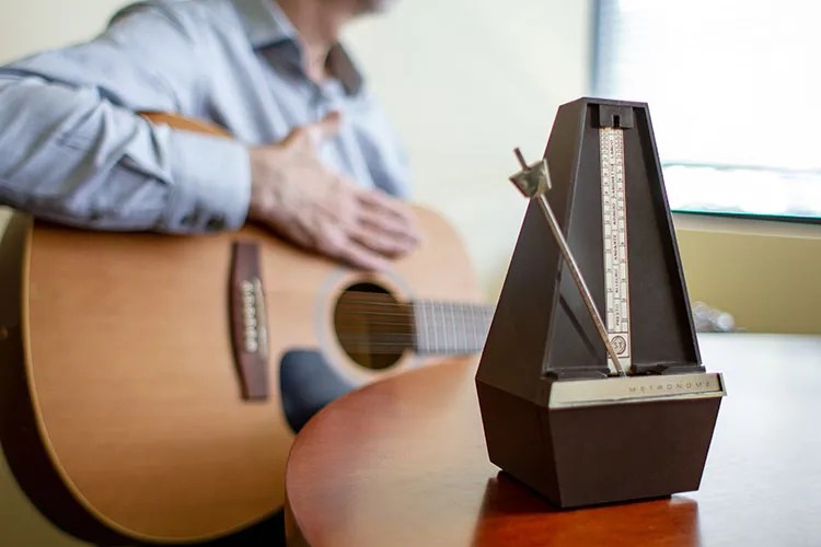 guitar player seated with a metronome