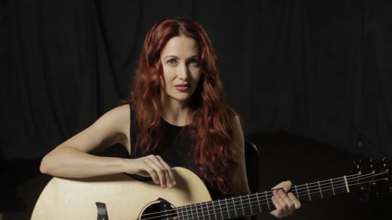 Gretchen Menn seated with acoustic guitar