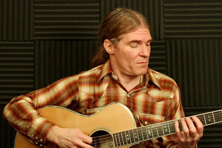 Tim Bertsch demonstrating an exercise from this weekly workout on his acoustic guitar