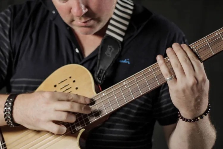 Jeff Gunn close up demonstrating how to play harmonics on acoustic guitar neck