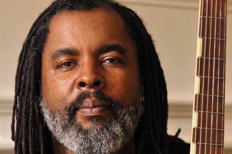 Close up view of Alvin Youngblood Hart's face and the upright neck of his acoustic guitar