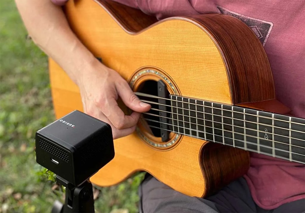 Acoustic guitarist using Audigo device to record their playing