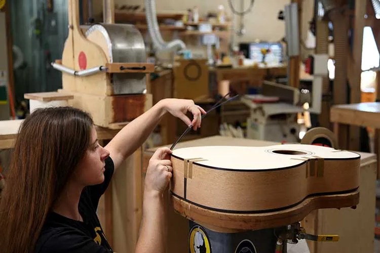 Olivia Elia binding an acoustic guitar