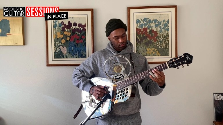 buffalo nichols playing his guitar against a wall of art