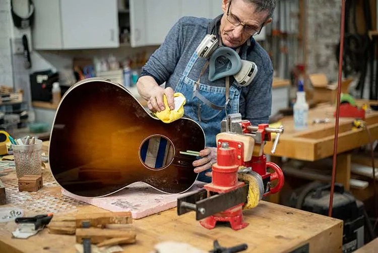 Luthier Jeff Jewitt buffing acoustic guitar