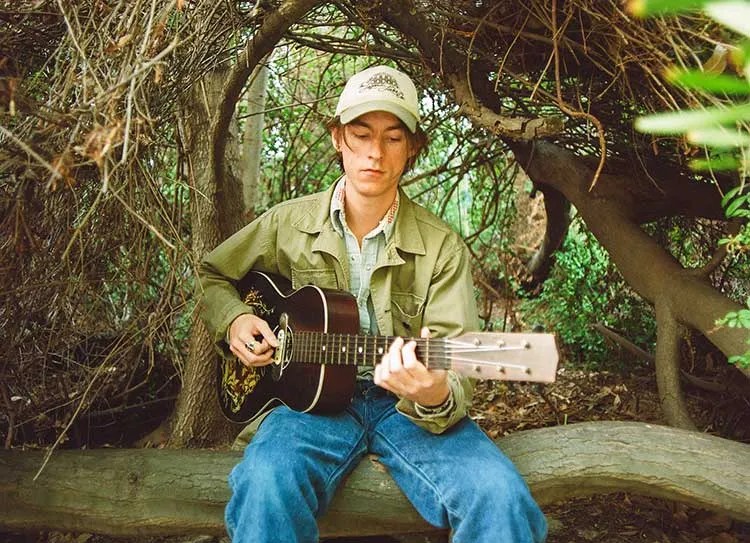 Cameron Knowler playing an acoustic guitar