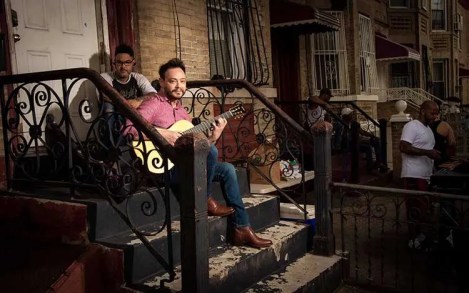 Charlie Rauh playing guitar on a stoop