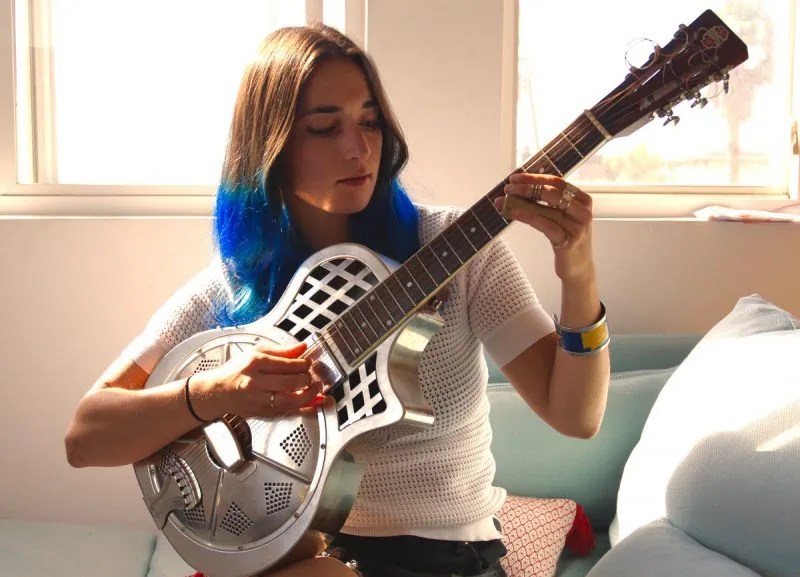 guitarist christina vane playing slide on a resonator guitar