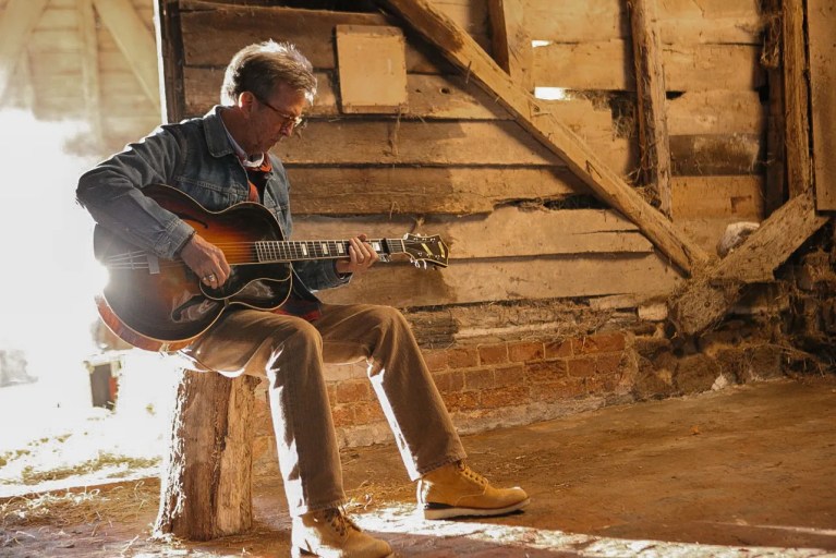 Guitarist Eric Clapton seated with an acoustic guitar