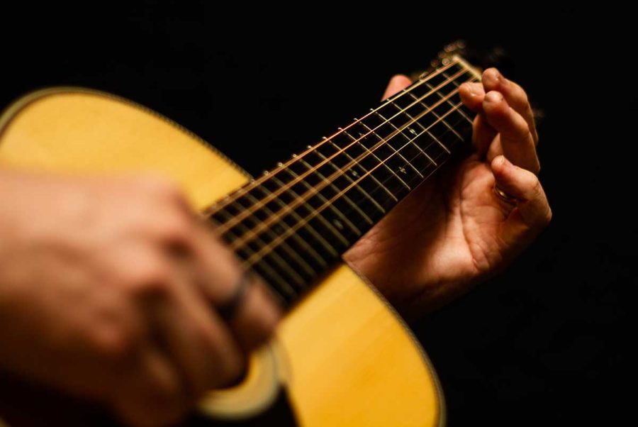 close up of hands playing acoustic guitar