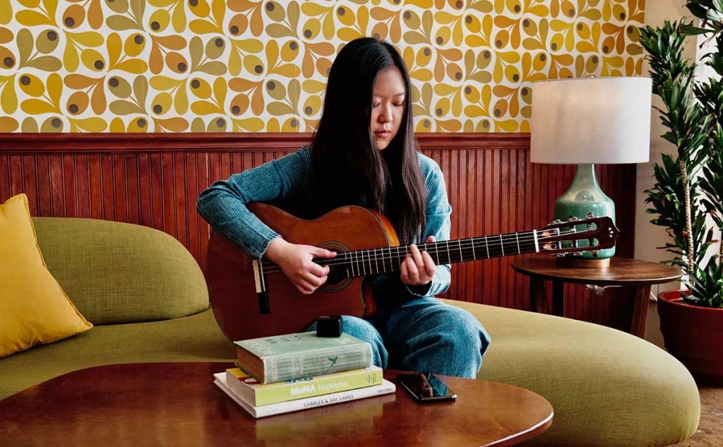 A guitarist records herself using the Audigo wireless microphone/app.