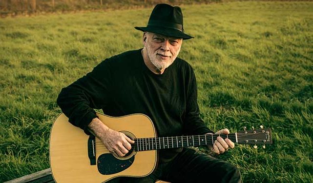 guitar player David Gilmour sitting in a field