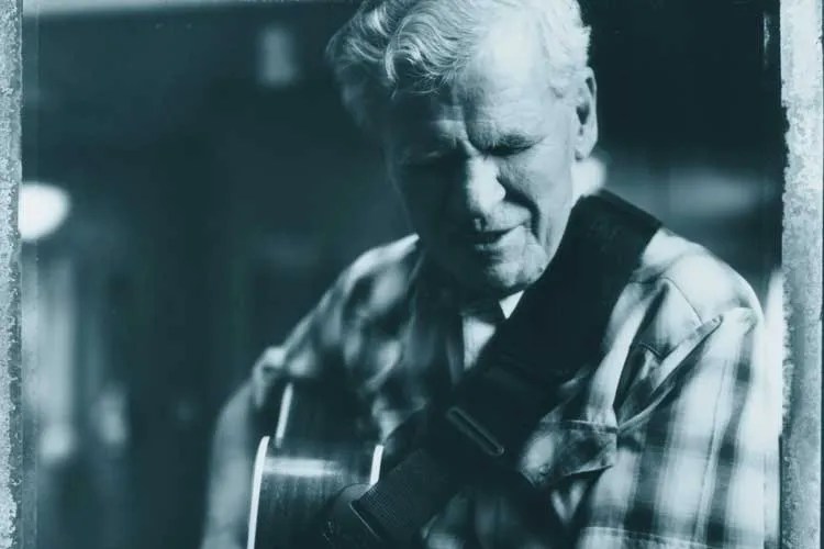 Doc Watson performing on acoustic guitar. Photo by Blair Jensen