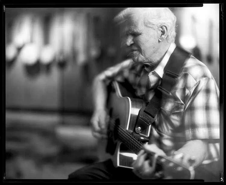 Doc Watson playing an acoustic guitar