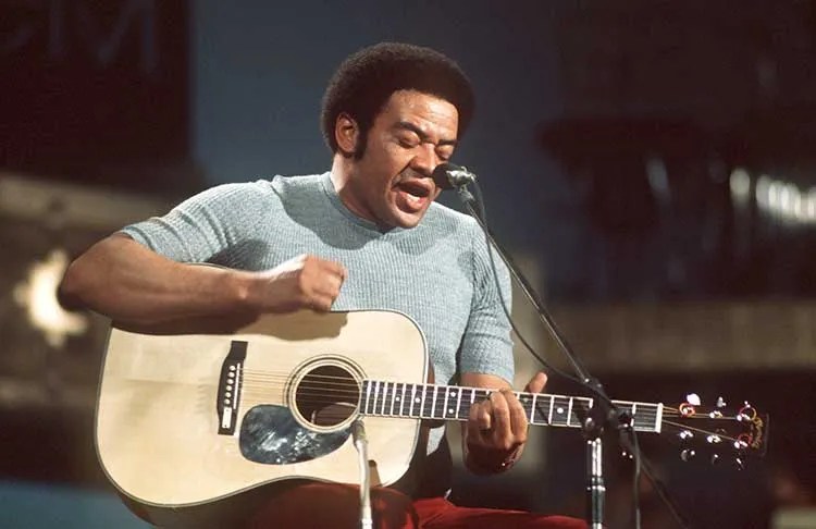 Bill Withers playing acoustic guitar and singing