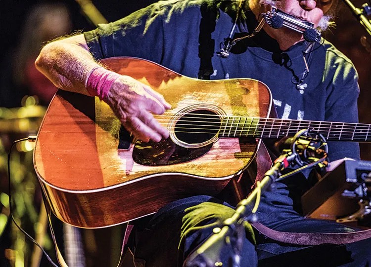 Stylized photo of a guitarist playing a dreadnought acoustic guitar. Photo by Jay Blakesberg