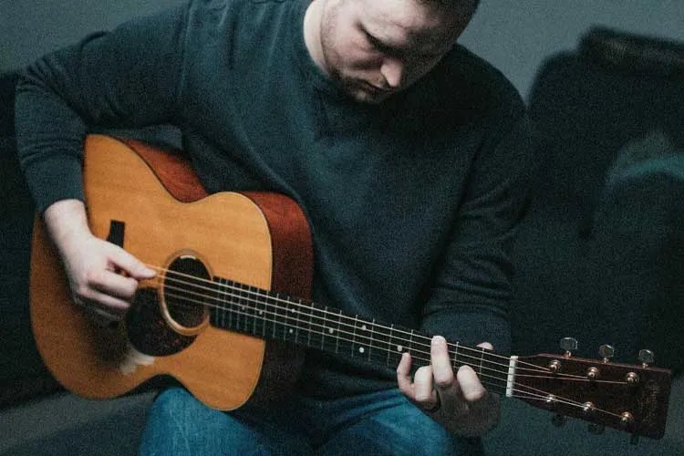 fingerstyle acoustic guitar player seated photo by brendan hollis