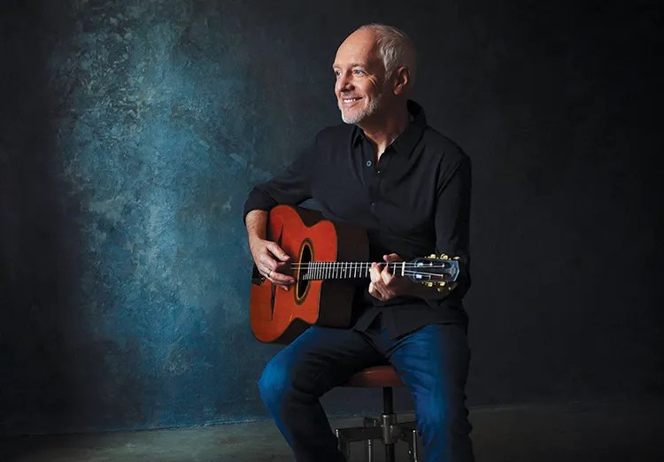 Peter Frampton standing with acoustic guitar. Photo by Gregg Roth