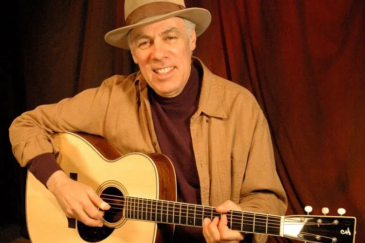 Fred Sokolow seated with acoustic guitar