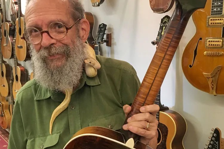 George Gruhn holding a guitar in his shop