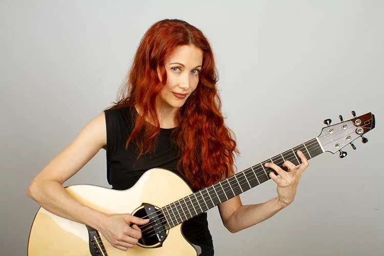 Gretchen Menn plays an acoustic guitar