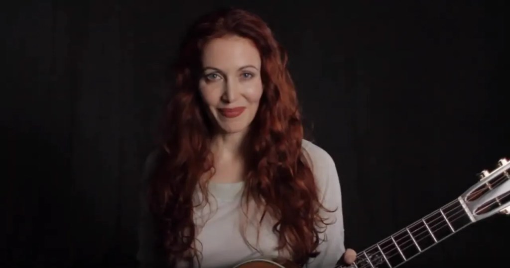 Gretchen Menn poses with acoustic guitar.