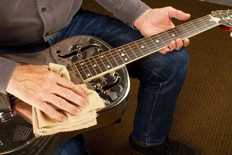 guitarist holds a resonator guitar and cleans it