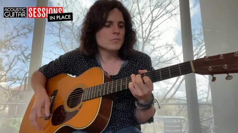 Hamish Anderson performing "Morning Light" on his acoustic guitar in front of a window