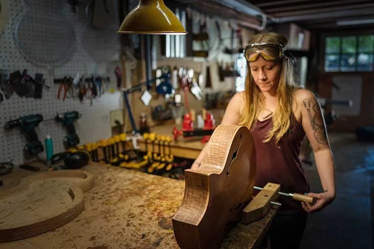 Luthier Maegen Wells in her workshop with an archtop guitar