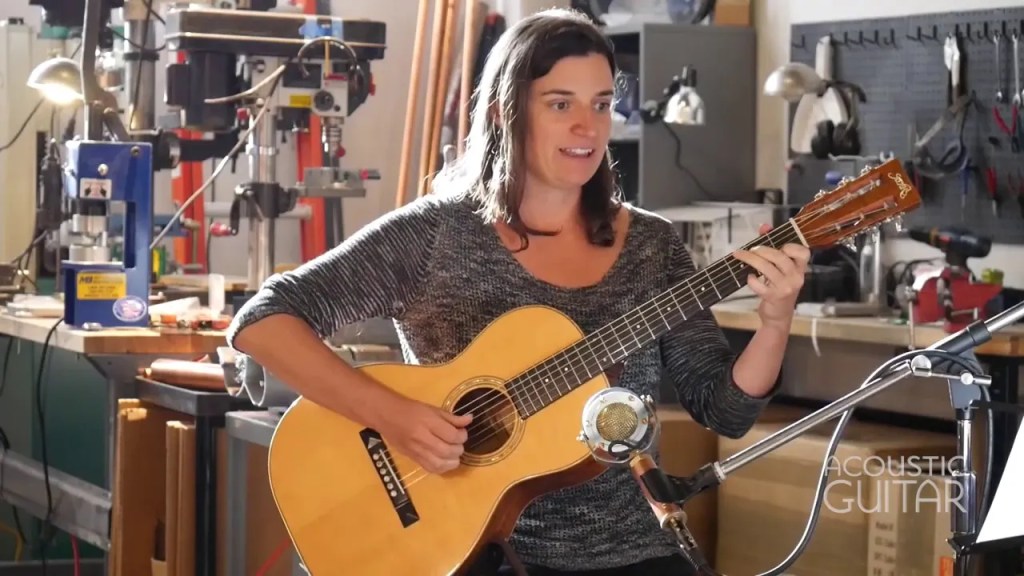 Jamie Stillway smiles with her guitar in a workshop