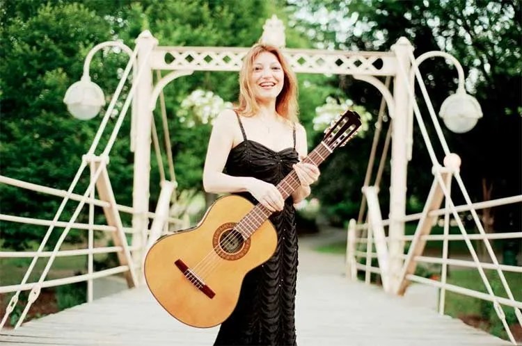 Irene Gómez holding acoustic guitar on bridge