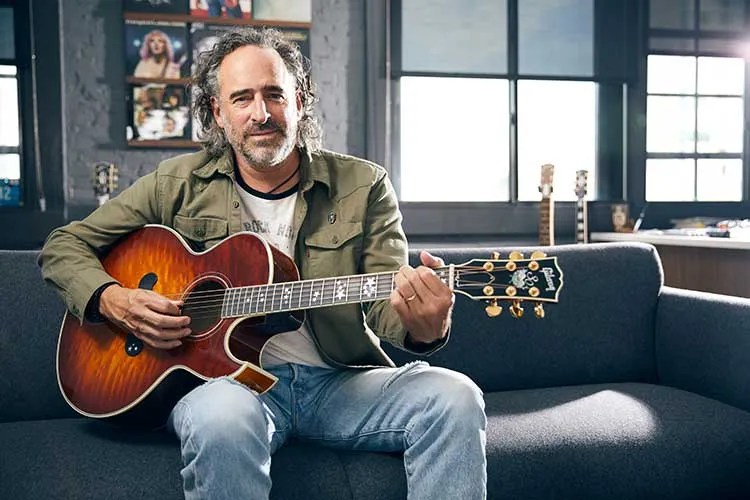 James “JC” Curleigh, CEO of Gibson Guitars, seated holding an acoustic guitar