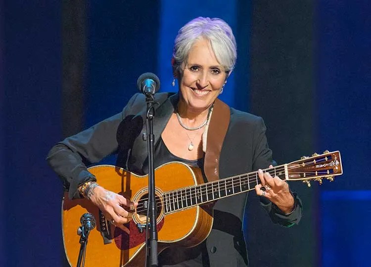 Joan Baez performing acoustic guitar onstage during a concert