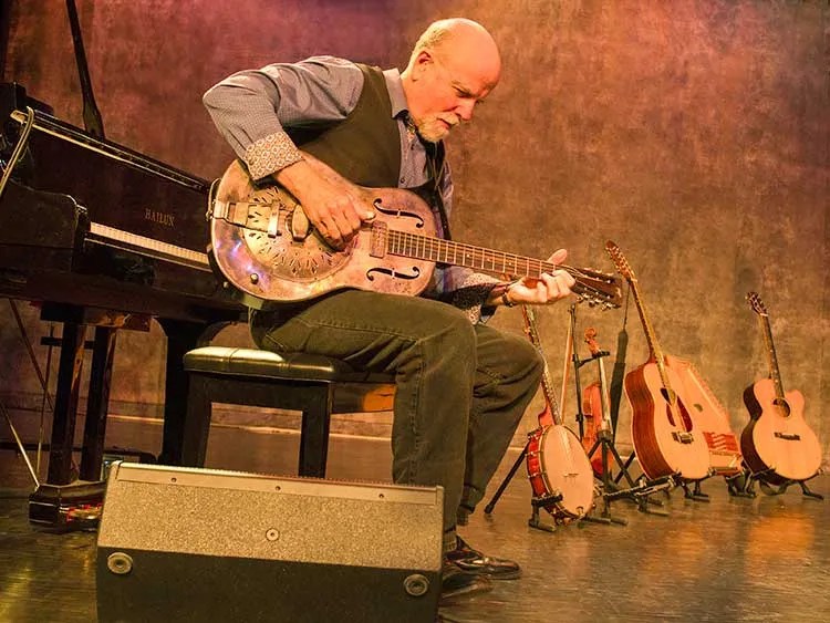 John McCutcheon playing guitar onstge