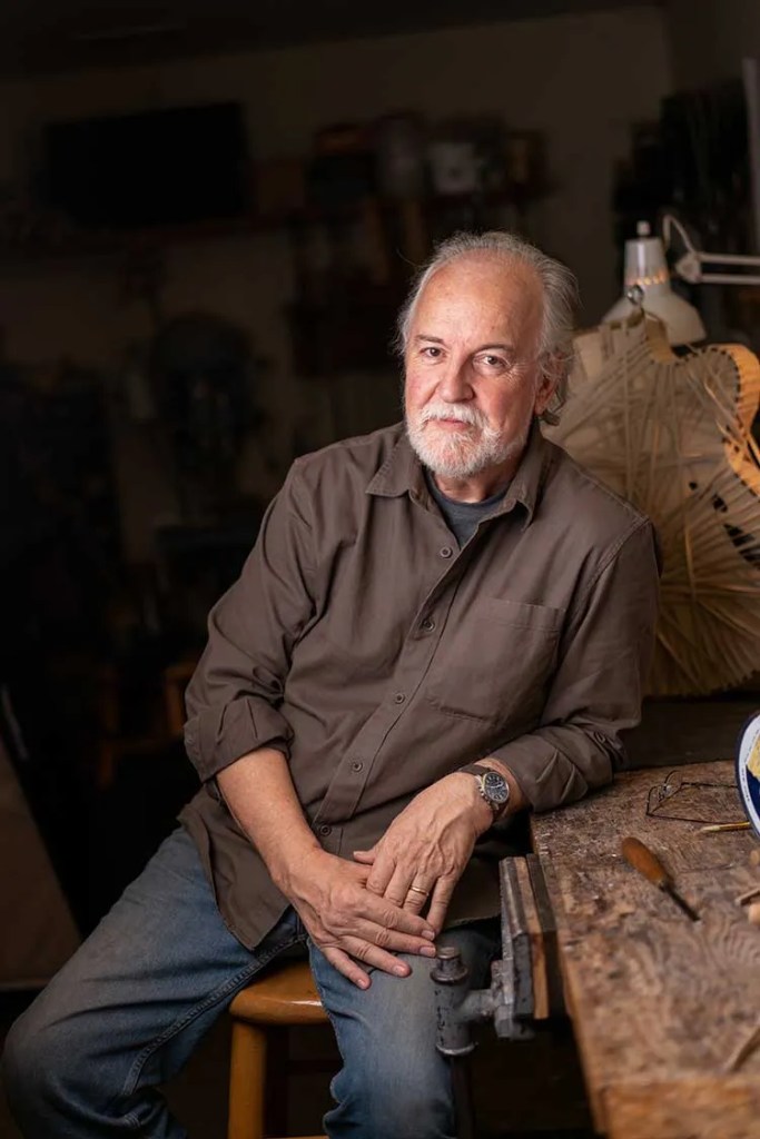 Luthier John Monteleone seated at his workbench in his guitar workshop