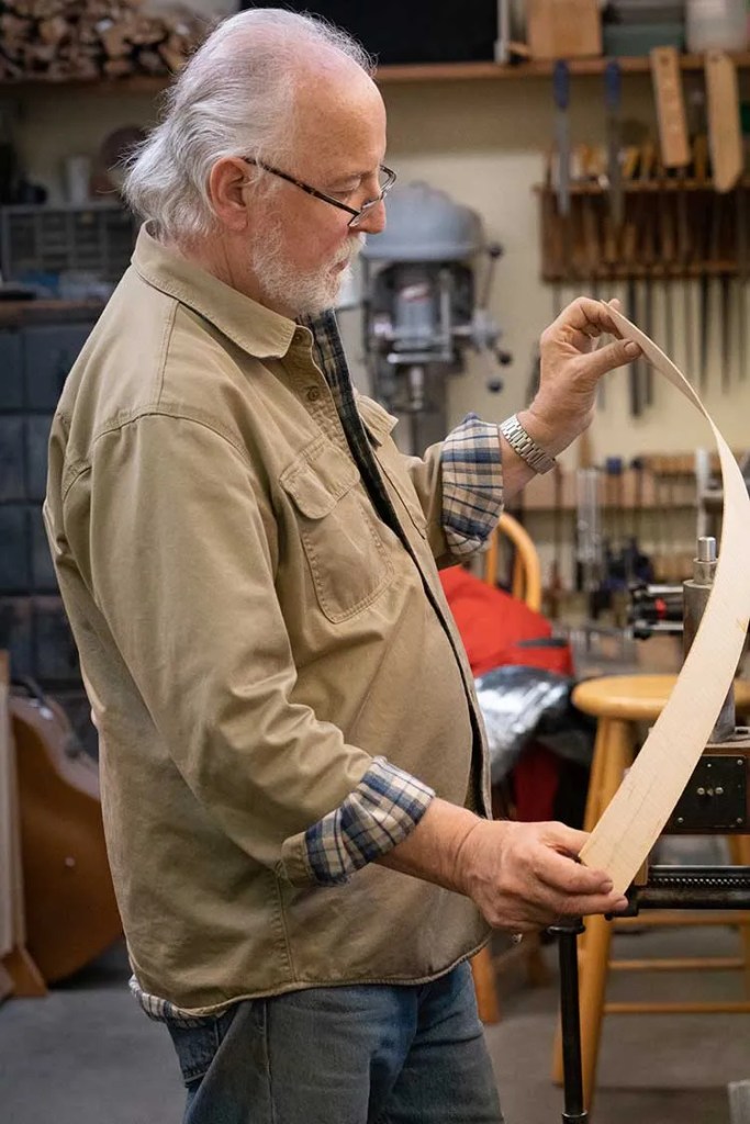 John Monteleone holding a thin strip of wood veneer