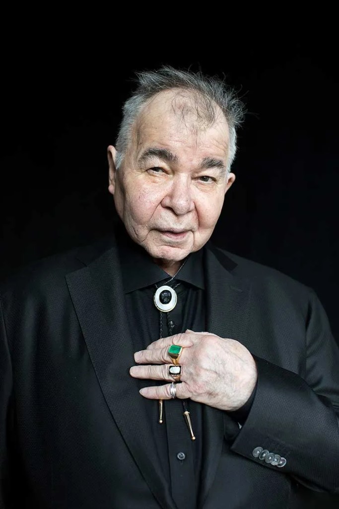 John Prine in his older years in a black suit with bolo tie