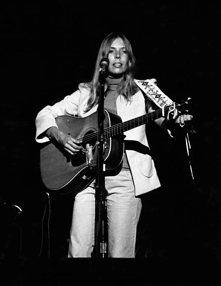 Joni Mitchell onstage with acoustic guitar