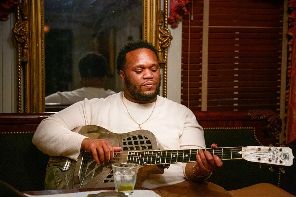 Jontavious Willis seated playing a National resonator guitar. Photo by Willam Pirandello