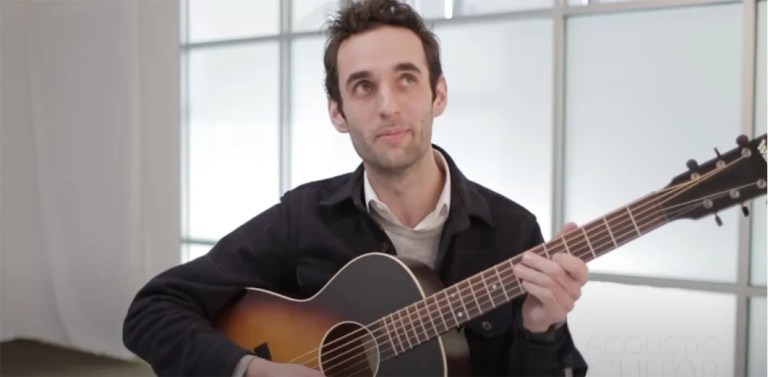 Juliian lage, seated with guitar, performs in the Acoustic Guitar studio